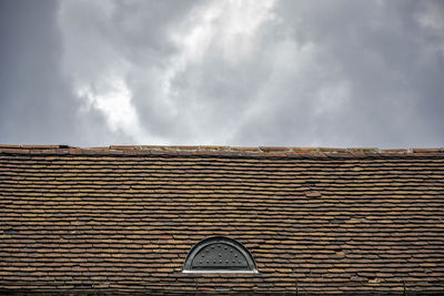 Rundown old roof made from terracotta tiles against cloudy sky background. copy space.