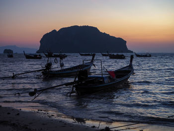 Silhouette boat moored on sea against sky during sunset