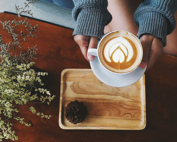 High angle view of woman holding coffee cup on table