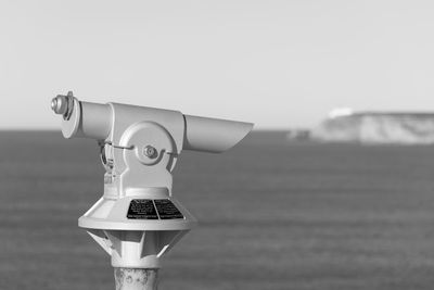 Close-up of coin-operated binoculars by sea against clear sky