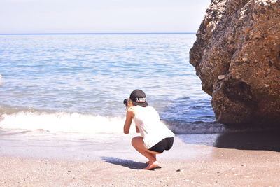 Full length of young woman on beach against clear sky