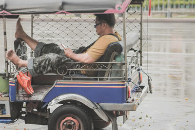 Side view of men sitting on road in city