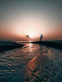 Seagulls flying over sea against sky during sunset