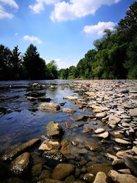 Surface level of stones by river against sky