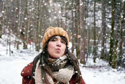 Portrait of a young woman during snowfall. winter clothes, sending a kiss.