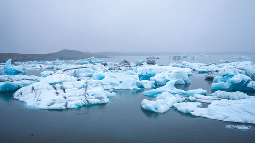 Ice floating on sea against sky during winter
