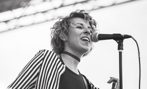 Low angle view of woman singing on microphone