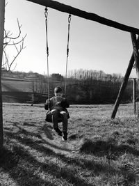 Rear view of boy on swing at playground