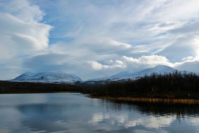 Scenic view of lake by mountains against sky