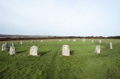 Stone materials on grassy field against cloudy sky