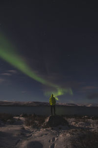 Rear view of man standing on land against sky at night