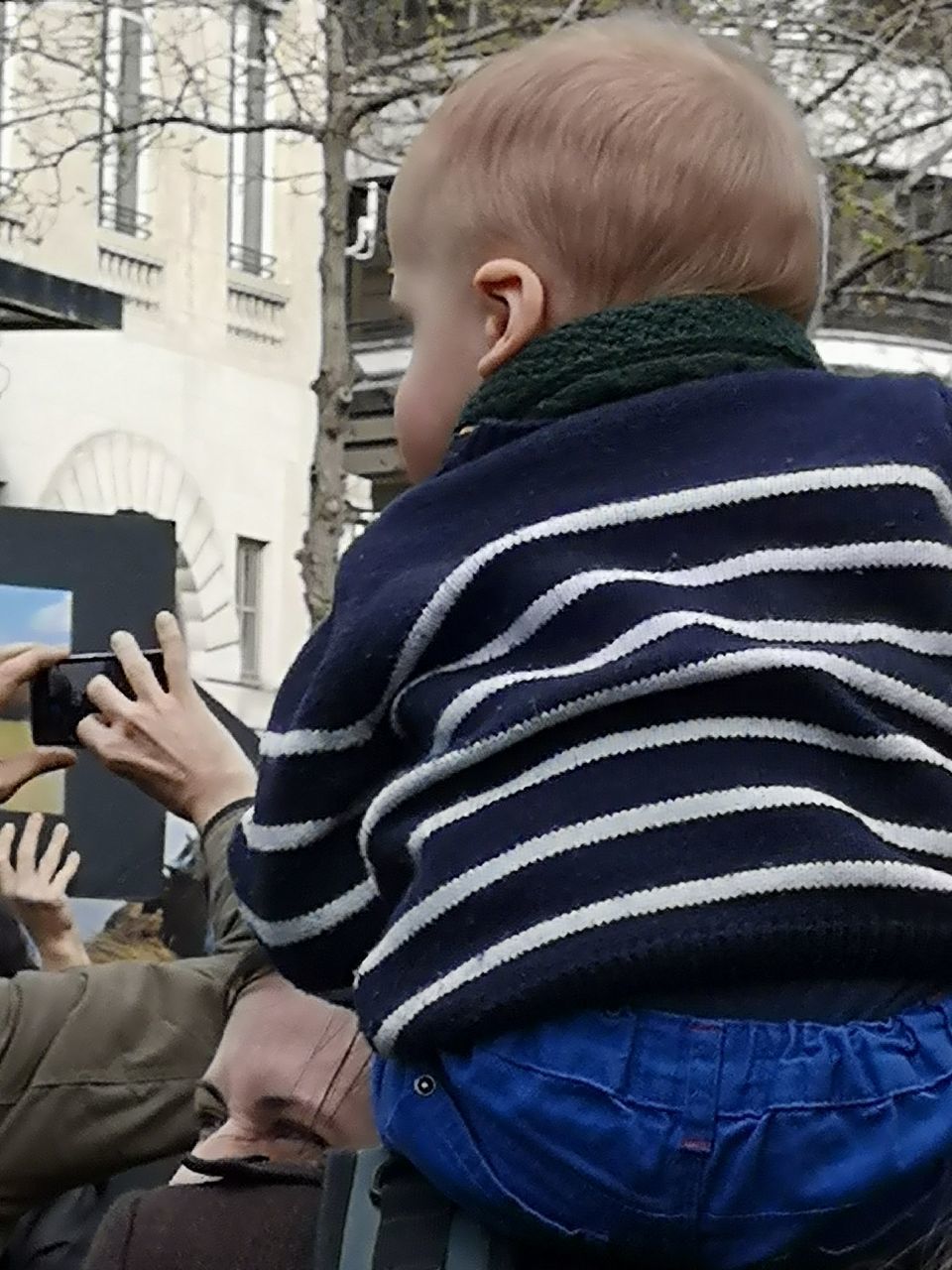 REAR VIEW OF BOY STANDING ON MOBILE PHONE IN OFFICE