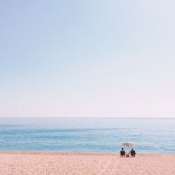 People on beach against clear sky