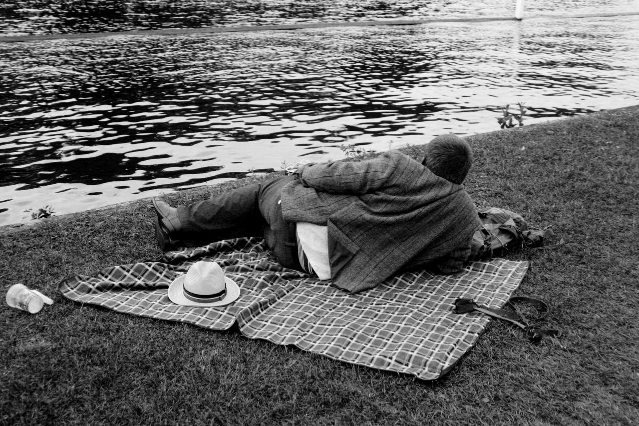 one person, relaxation, lying down, men, full length, sleeping, leisure activity, real people, social issues, day, lifestyles, nature, water, hat, casual clothing, resting, outdoors, hopelessness