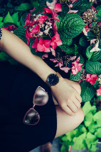 Midsection of woman with sunglasses sitting by plants