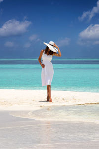 Woman standing at beach against sea