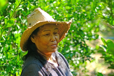 Close-up of woman wearing wicker hat against plants