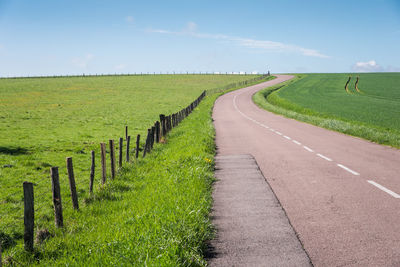  road amidst field against sky. country road amidst field