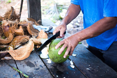 Close-up of man cutting coconut