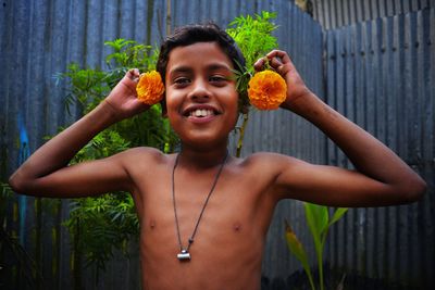 Portrait of shirtless boy holding flowers