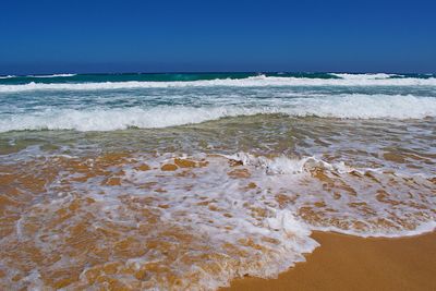 Scenic view of beach against clear blue sky