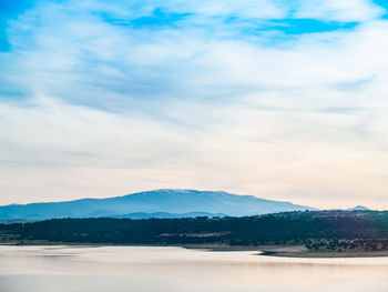 Scenic view of lake by mountains against sky