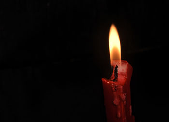 Close-up of burning candle against black background