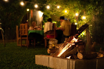 People sitting outdoors by bonfire during christmas at night