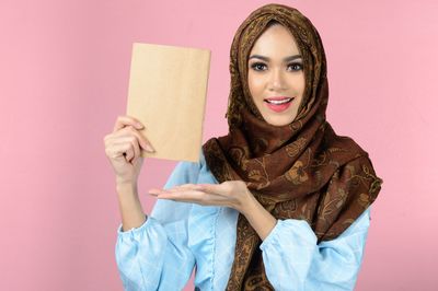 Portrait of smiling young woman against wall
