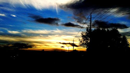 Silhouette of trees against cloudy sky