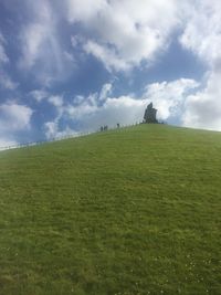 Scenic view of grassy field against cloudy sky