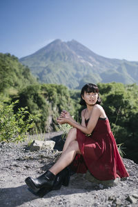 Woman sitting on landscape against mountains