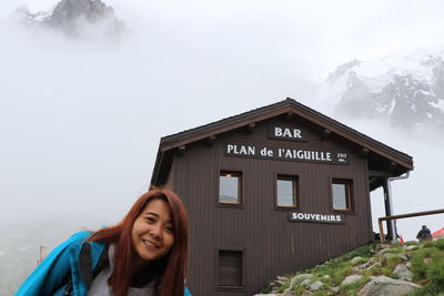 Portrait of smiling young woman standing against building