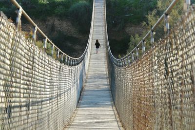 Rear view of girl walking on footbridge