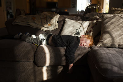 Toddler boy sleeping on his stomach on couch at home in pretty light