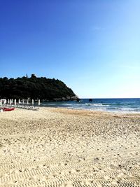 Scenic view of beach against clear blue sky