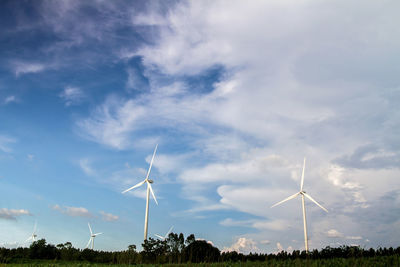 Wind turbines on field against sky