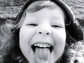 Close-up portrait of cute girl sticking out tongue outdoors