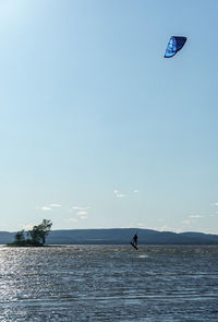 Person paragliding over sea against sky