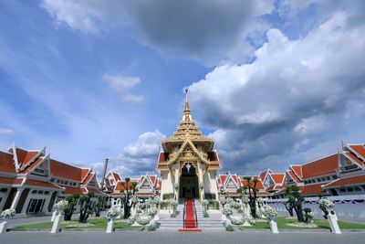 Low angle view of temple against cloudy sky during sunny day