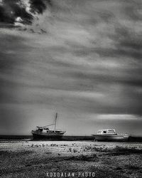 Boats in sea against cloudy sky