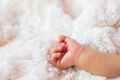 Cropped image of baby hand on bed