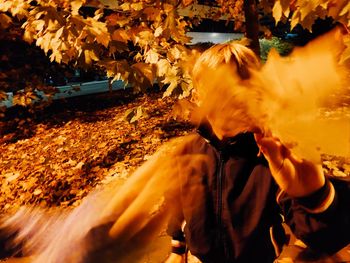 Rear view of man holding autumn leaves