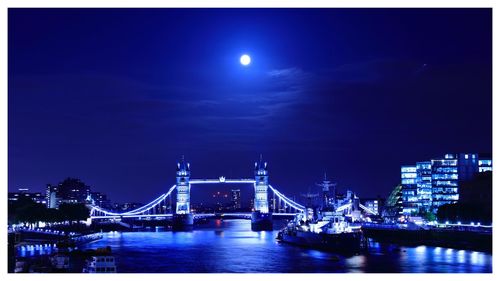 Illuminated bridge over river at night