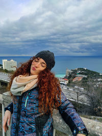 Beautiful woman standing by sea against sky