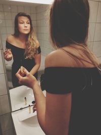 Rear view of woman standing in bathroom