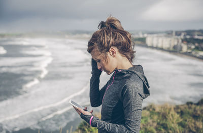 Woman using mobile phone while standing on sea shore