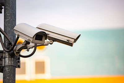 Close-up of security camera on pole against sky