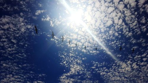 Low angle view of sun shining through clouds in sky