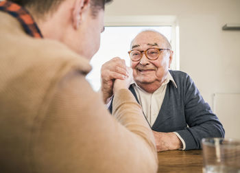 Smiling senior man arm wrestling with young man